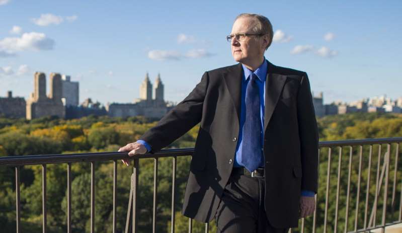 一名穿着西装和领带站在栅栏旁边的男子：2015年，微软联合创始人Paul G. Allen。