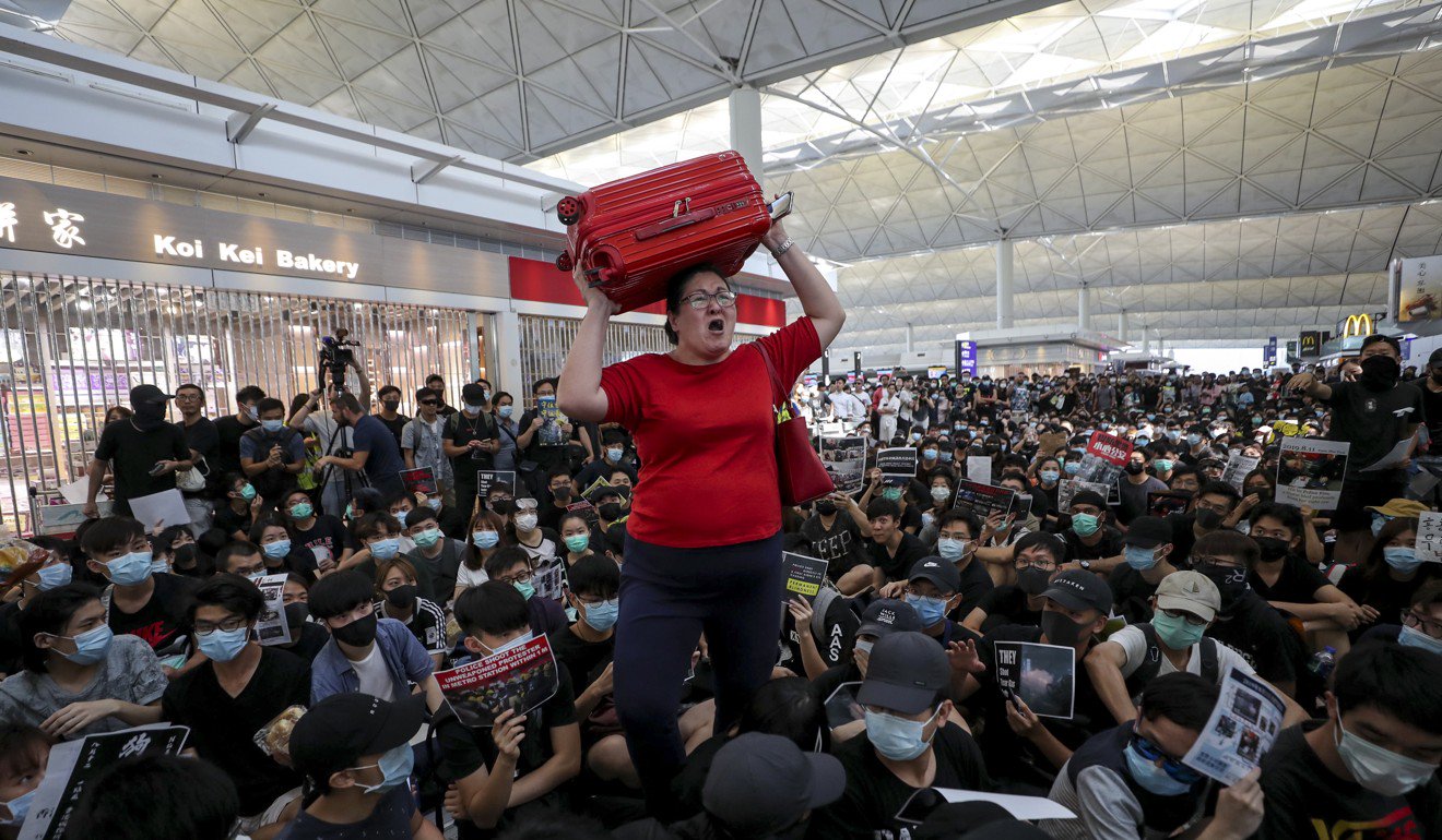 8月13日，一名旅客在香港國際機場的抗議者面前涉水。照片：曾蔭權