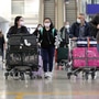 戴著口罩的旅行者穿過中國香港國際機場的到達大廳。 （彭博）