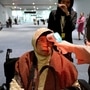 一名卫生官员在乘客到达机场时扫描其体温。代表性图片（AP）