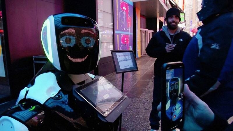 时代广场的行人与Promobot机器人互动，该机器人将向公众通报冠状病毒的症状 