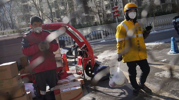 美團和京東的送貨員戴著口罩站在居民區外面 